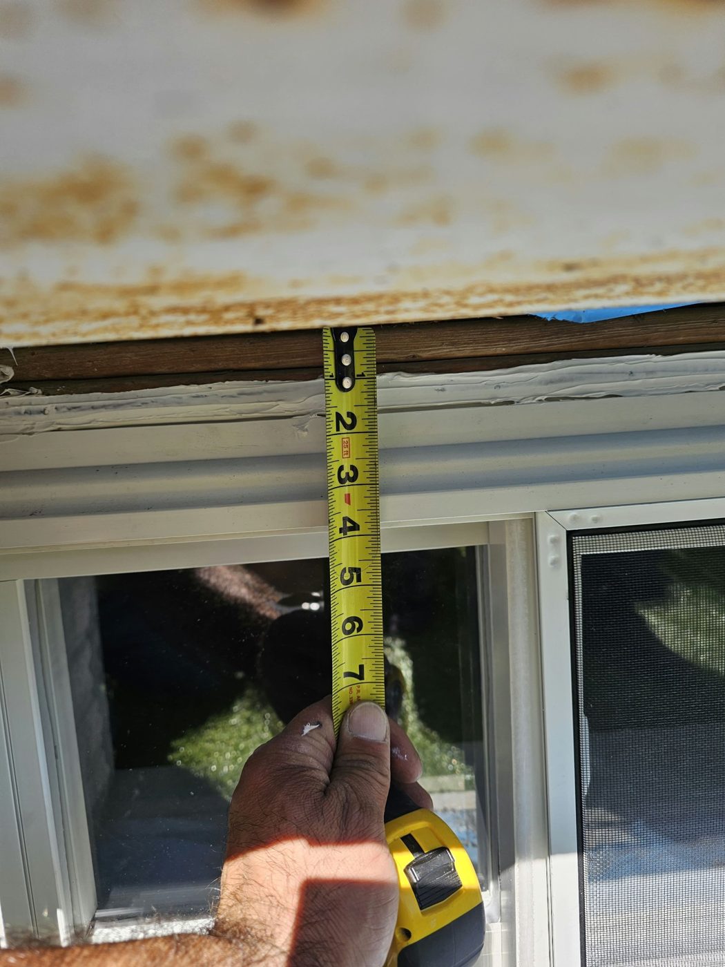 Measuring down from the existing metal above the window head to size an aluminum panel at 5101 Beach 51st Street, Sea Gate