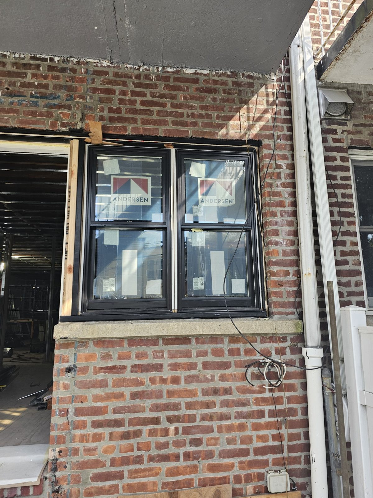 Pair of Andersen 400 Series double-hung windows with black exterior in a brick opening