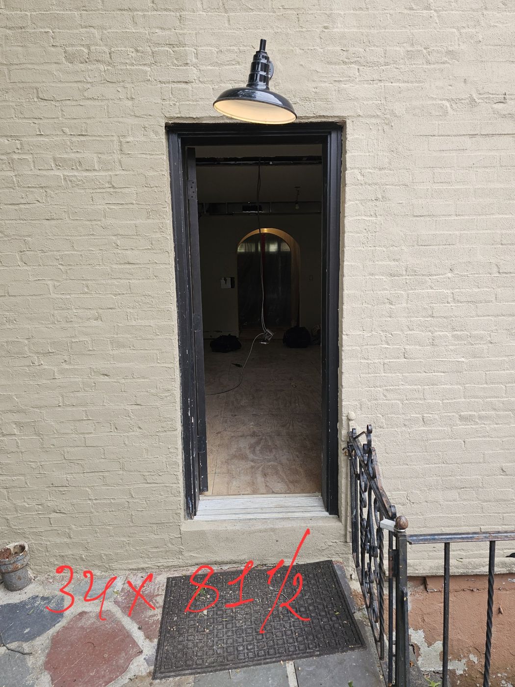 Existing exterior door opening in a painted brick wall, marked 34 by 81 and a half inches