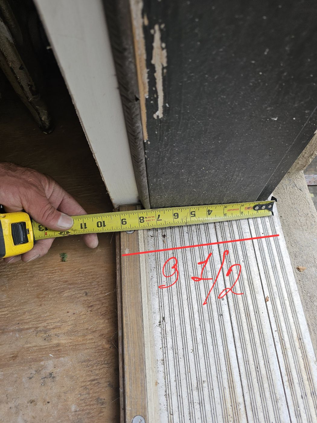 Tape measure across an existing door sill showing a depth of 9 and a half inches