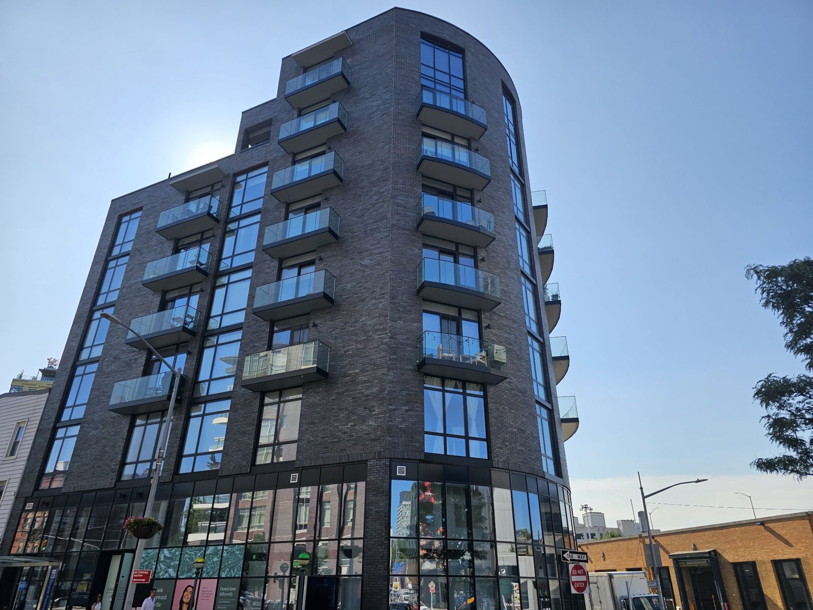 The Anable seen from Jackson Avenue: dark brick, columns of black-framed windows, glass balcony railings and a glazed ground floor