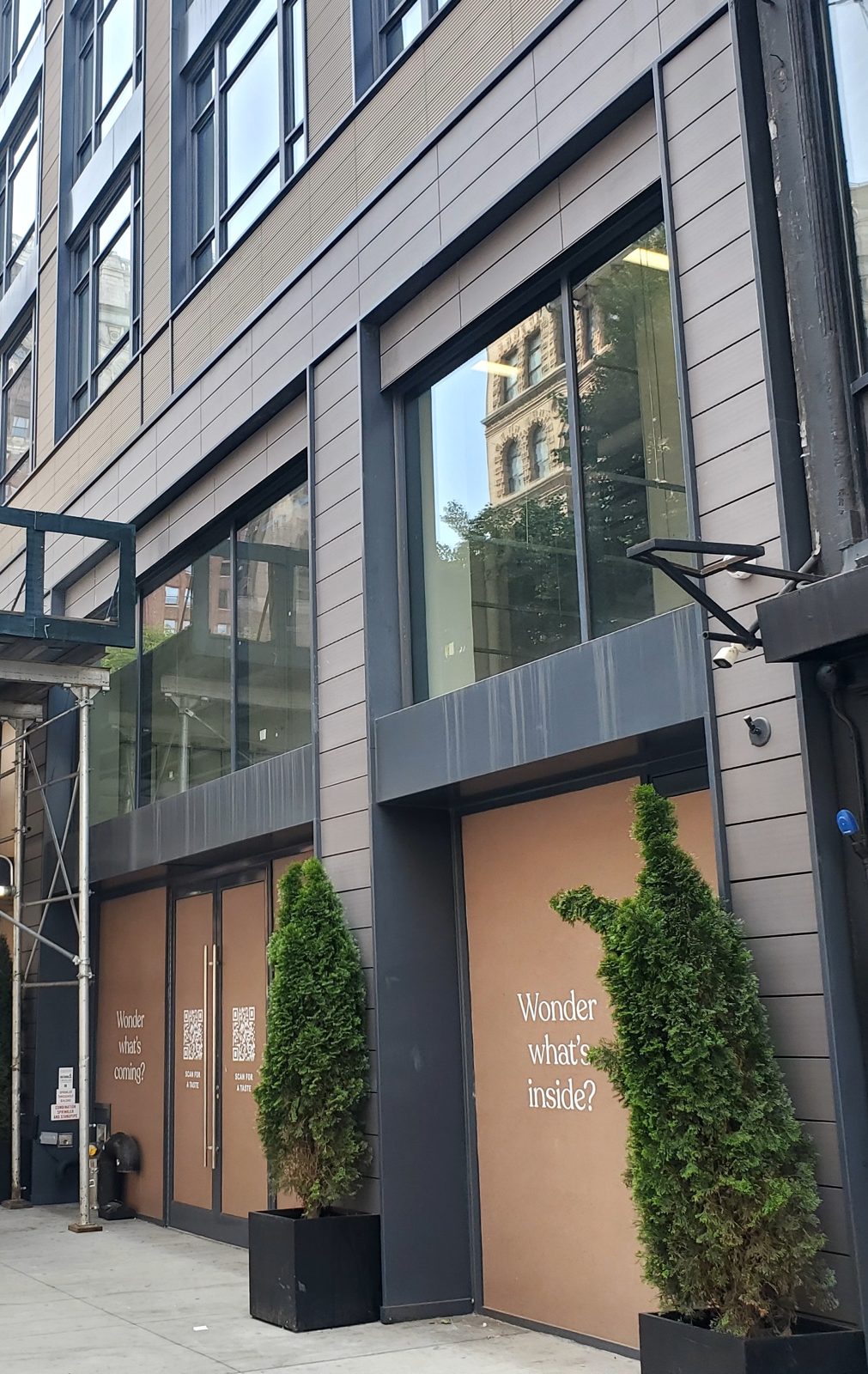 Ground-floor aluminum and glass storefront with a pair of glass entrance doors at 128 West 23rd Street, Manhattan, covered with tenant graphics before the restaurant opened