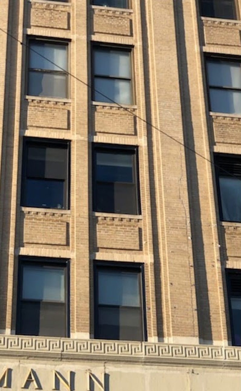 Dark aluminum double-hung windows set between brick piers at 165-19 Jamaica Avenue, Jamaica, Queens