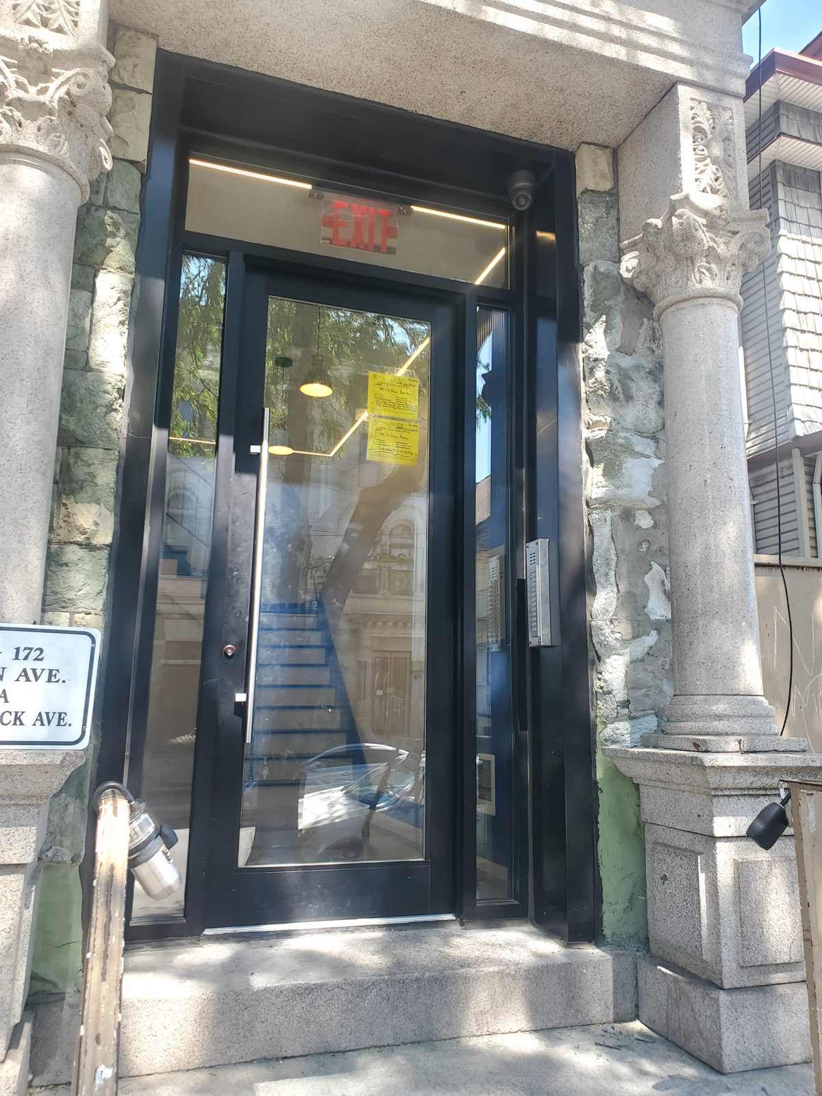 Black aluminum entrance door with full-height pull handle and intercom panel at 168-172 Ocean Avenue, Jersey City NJ