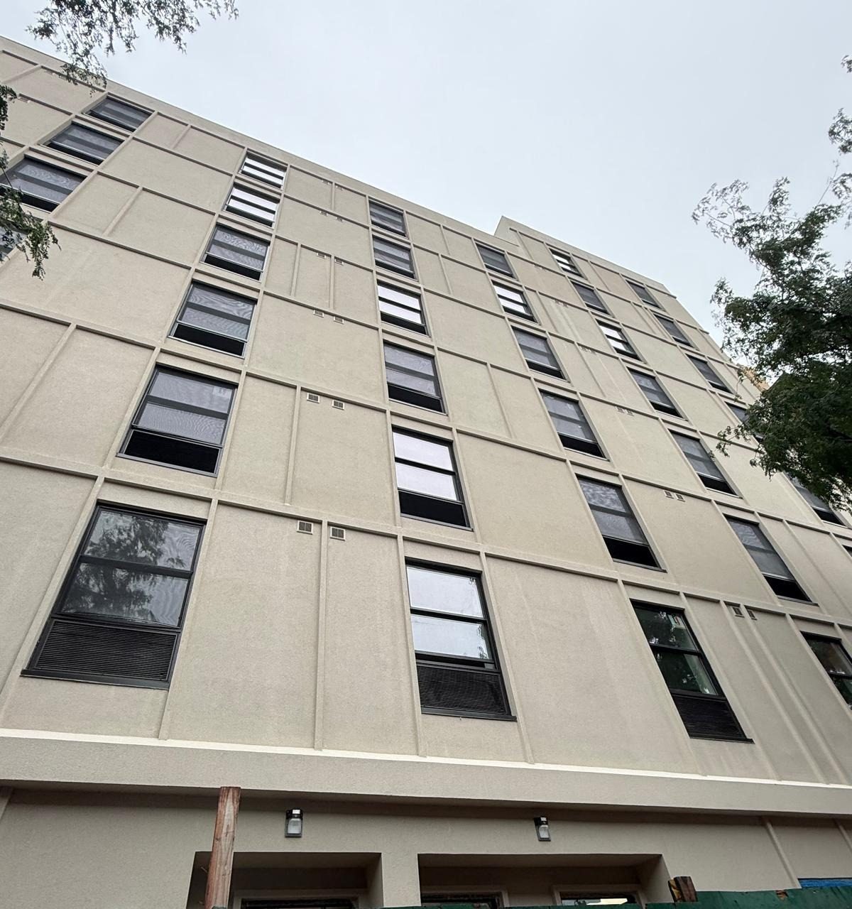 Dark-framed Crystal windows in vertical lines on the light stucco facade of the new building at 1763 Amsterdam Avenue, Manhattan