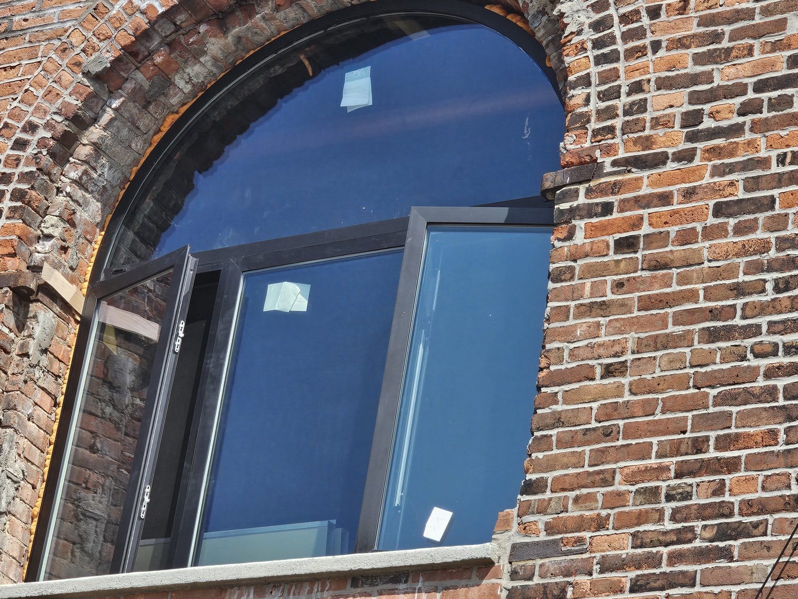 Close-up of out-swing aluminum casement sashes below a fixed arched lite at 185 Van Dyke Street, Red Hook