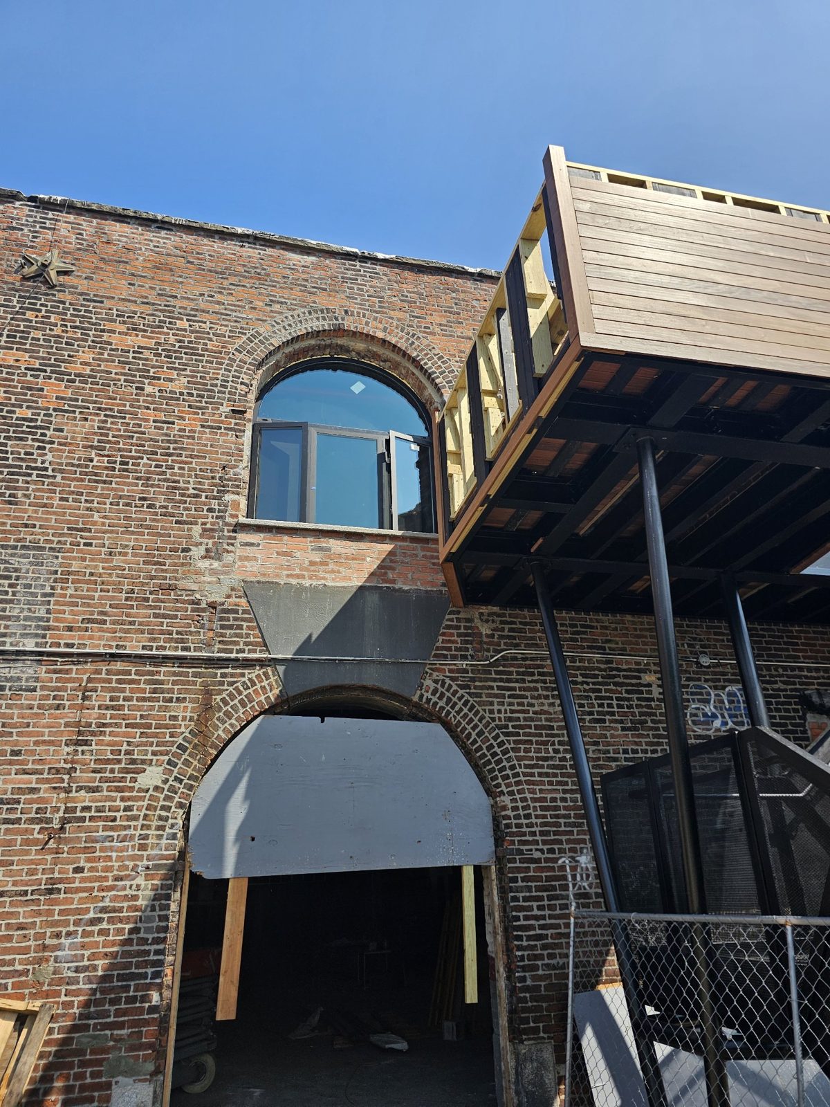 Arched aluminum window with out-swing casements above a brick archway at 185 Van Dyke Street, Red Hook