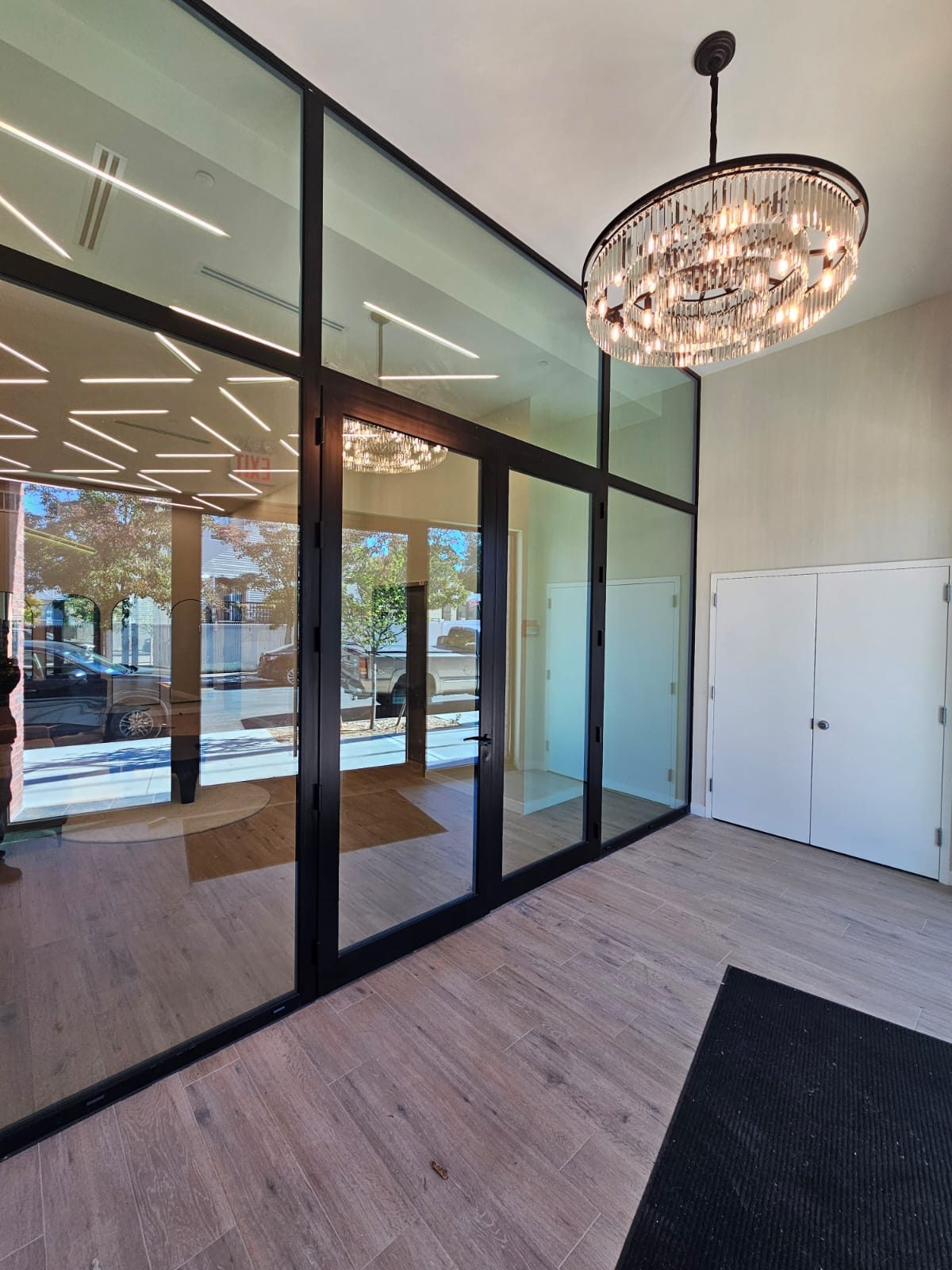 Interior black aluminium storefront section with a glass door, fixed lites and transoms in the entrance vestibule of 217 Main Street, Staten Island, seen from the vestibule