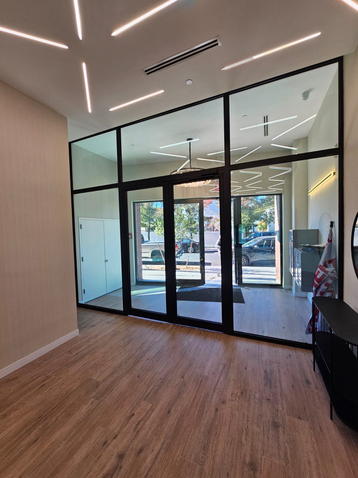 Interior black aluminium storefront partition with glass doors and transom lites separating the lobby from the vestibule at 217 Main Street, Staten Island, seen from the lobby