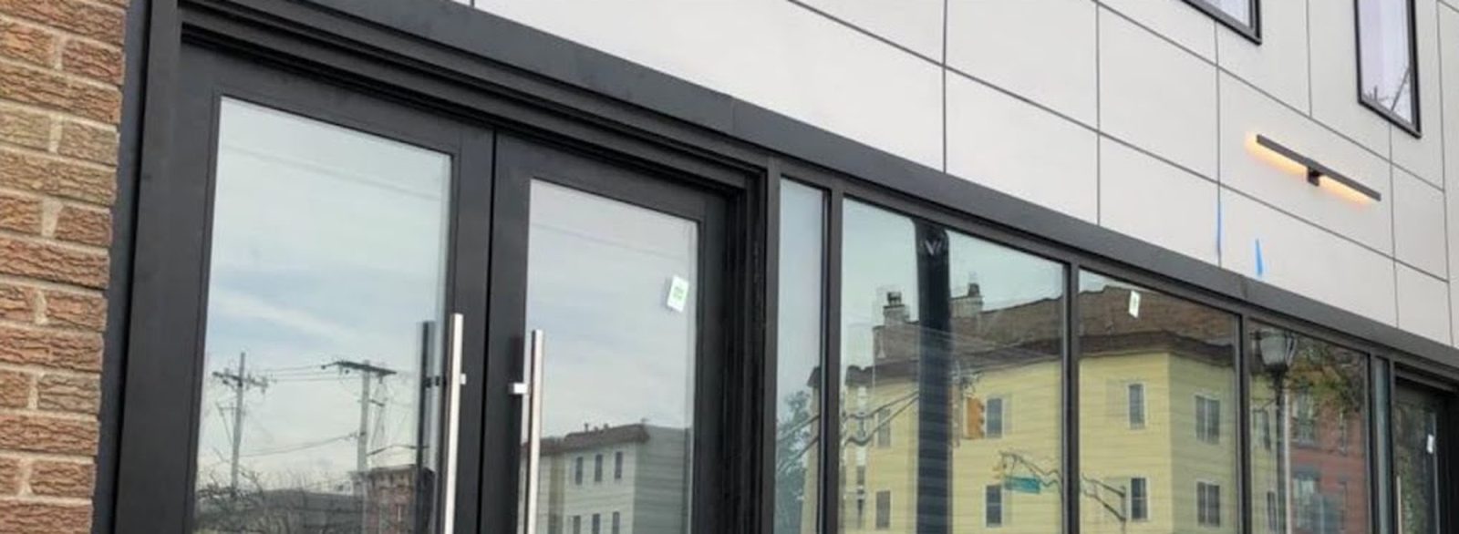 Black aluminum curtain wall storefront with a pair of medium-stile entrance doors at 237 Central Avenue, Jersey City, NJ