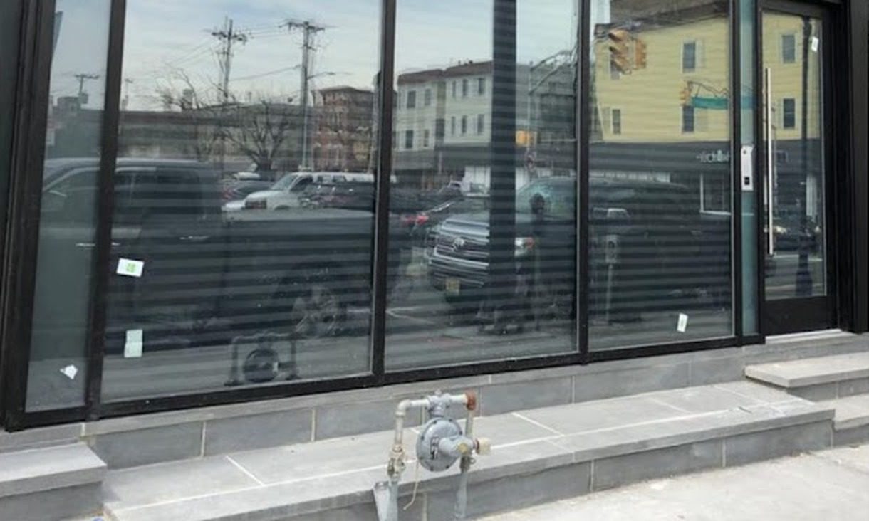 Black curtain wall with insulated glass units and a single aluminum entrance door at 237 Central Avenue, Jersey City