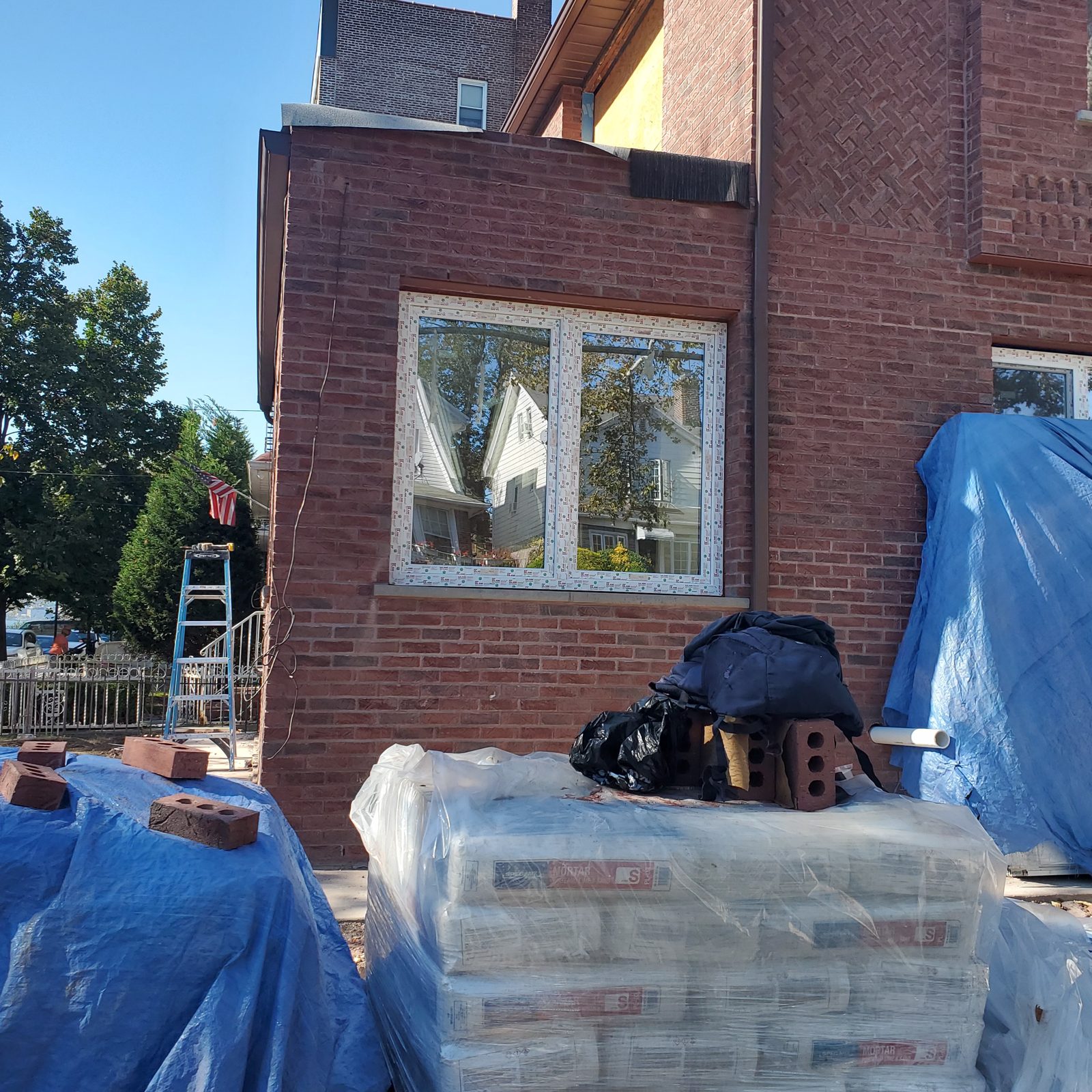 Two-part white uPVC window at the corner of the brick house at 24 74th Street, Brooklyn