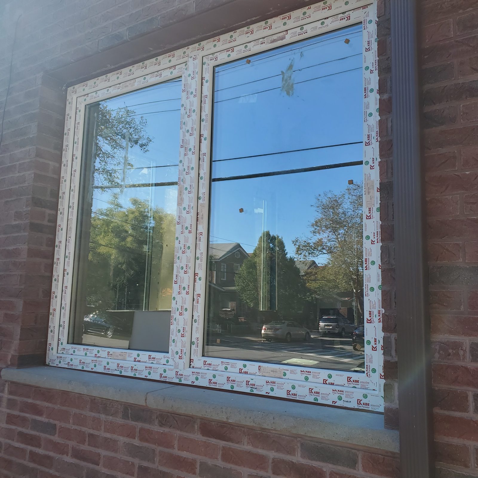 Close view of a two-part white uPVC window with factory protective film on the frame at 24 74th Street, Brooklyn
