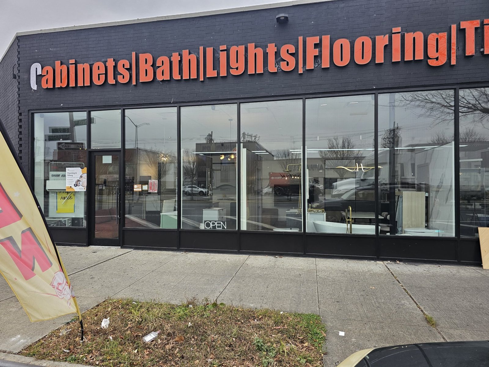 Straight-on view of the custom black storefront at 2461 Flatbush Avenue, Brooklyn, showing the single-leaf full-glass entry door and the showroom display behind clear low-E glass
