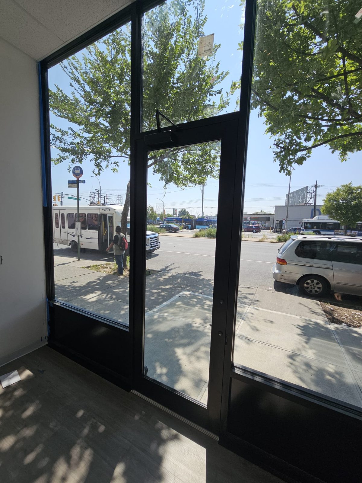 Interior view of the black aluminum storefront at 2461 Flatbush Avenue, Brooklyn, with a single medium-stile door, surface closer and transom above