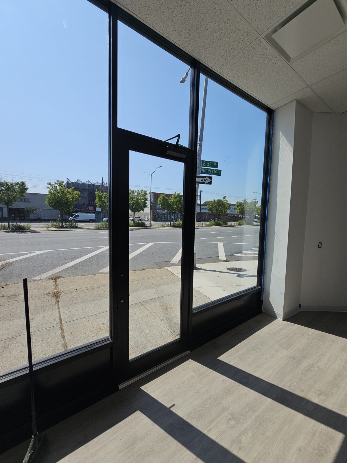 Interior view of a single medium-stile aluminum storefront door between full-height fixed lites at 2461 Flatbush Avenue, Brooklyn