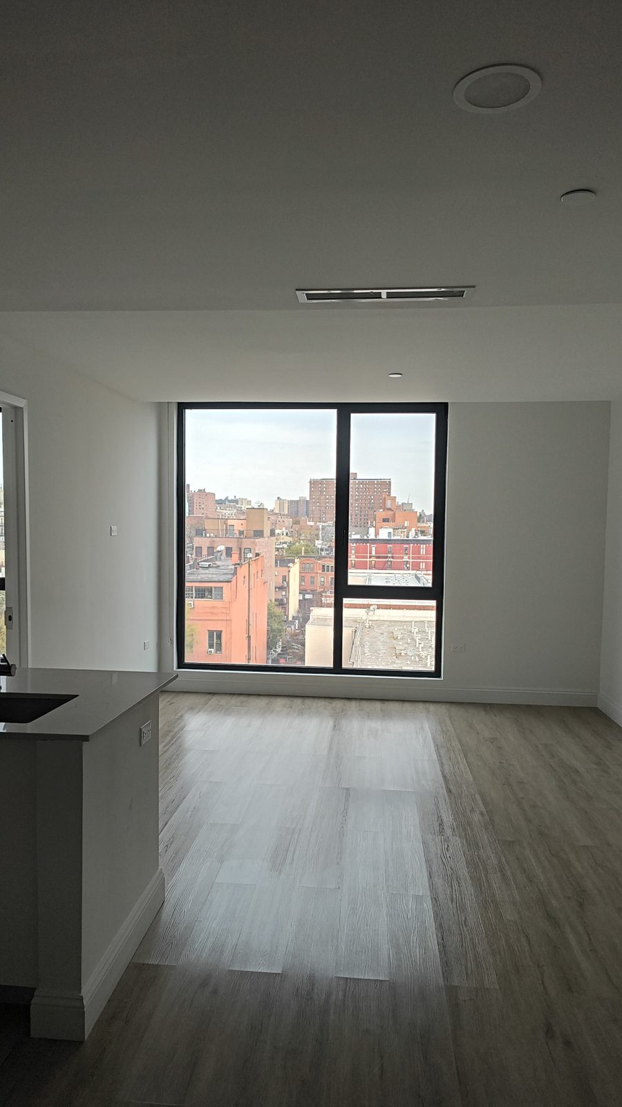 Living room window wall with a tilt-and-turn sash and open view across Manhattan at 2535 Frederick Douglass Boulevard, Harlem