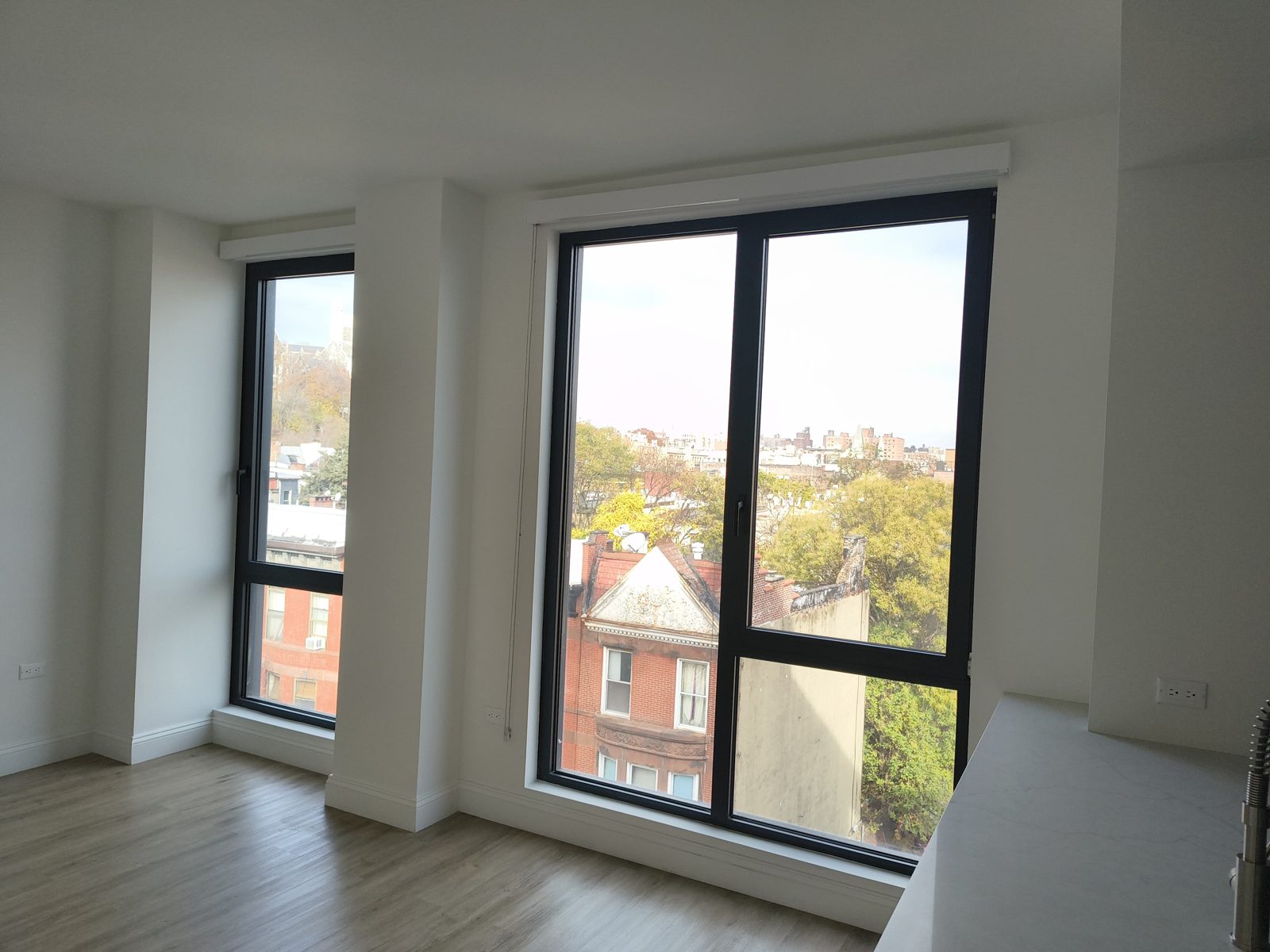 Two black aluminum tilt-and-turn windows with roller shades in a bedroom at 2535 Frederick Douglass Boulevard, Harlem, Manhattan