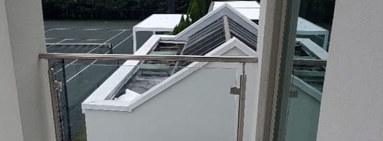 Stainless steel and glass railing spanning between columns on a balcony at 27 Runyan Avenue, Deal, NJ