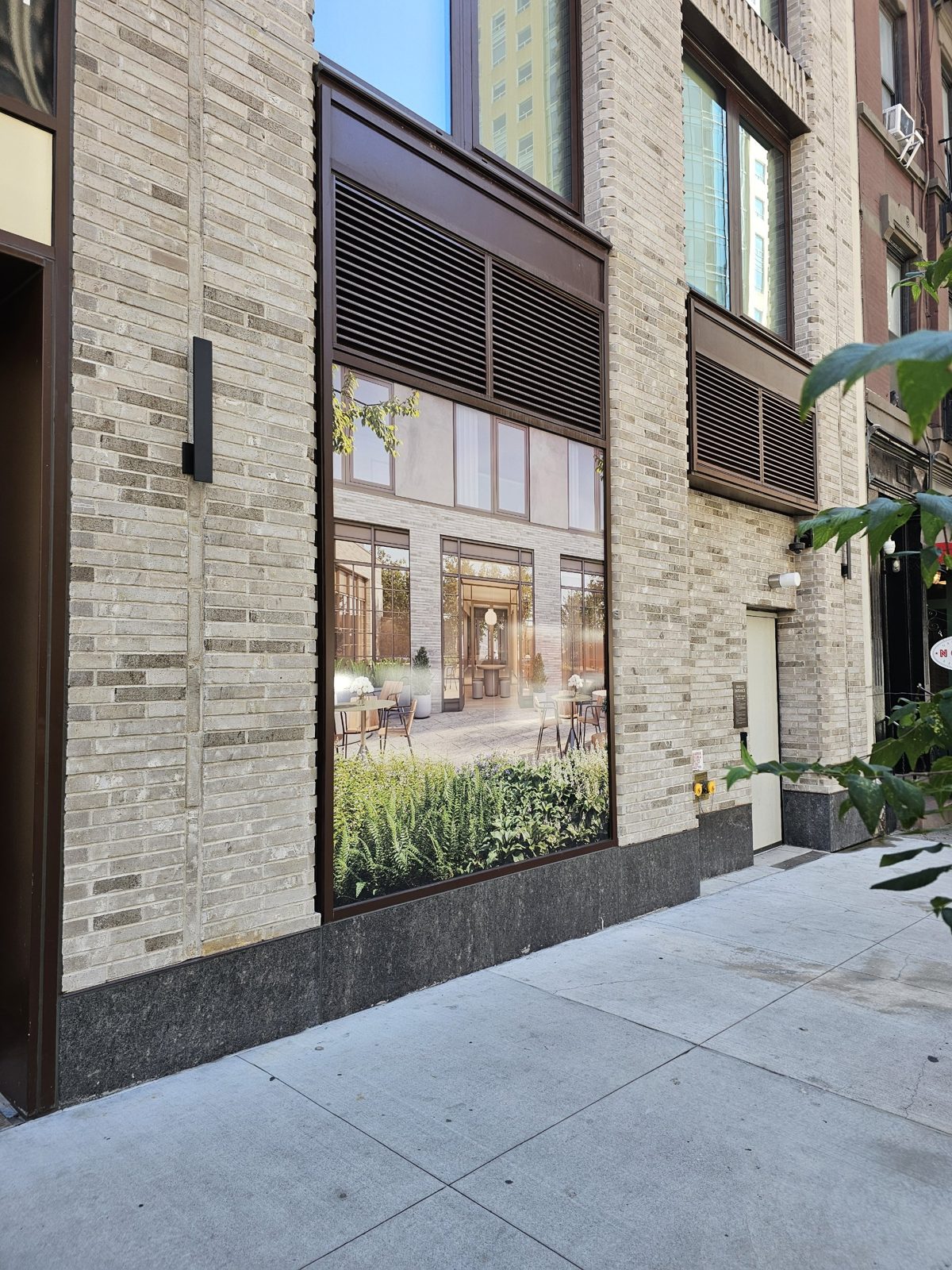 Louvred ventilation panel framed into the head of a curtain wall bay above a large fixed lite at 300 East 50th Street, Manhattan, all in the same dark bronze finish