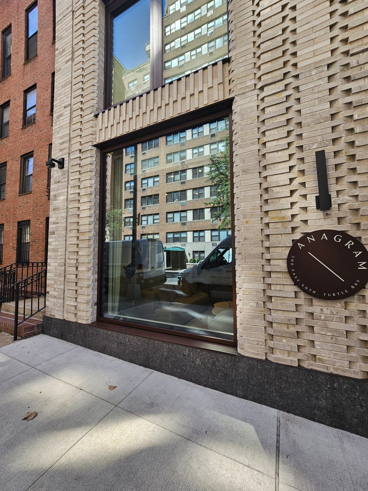 Glazed corner bay of the curtain wall at 300 East 50th Street, Manhattan, in a dark bronze frame with the round building sign mounted on the brick pier beside it