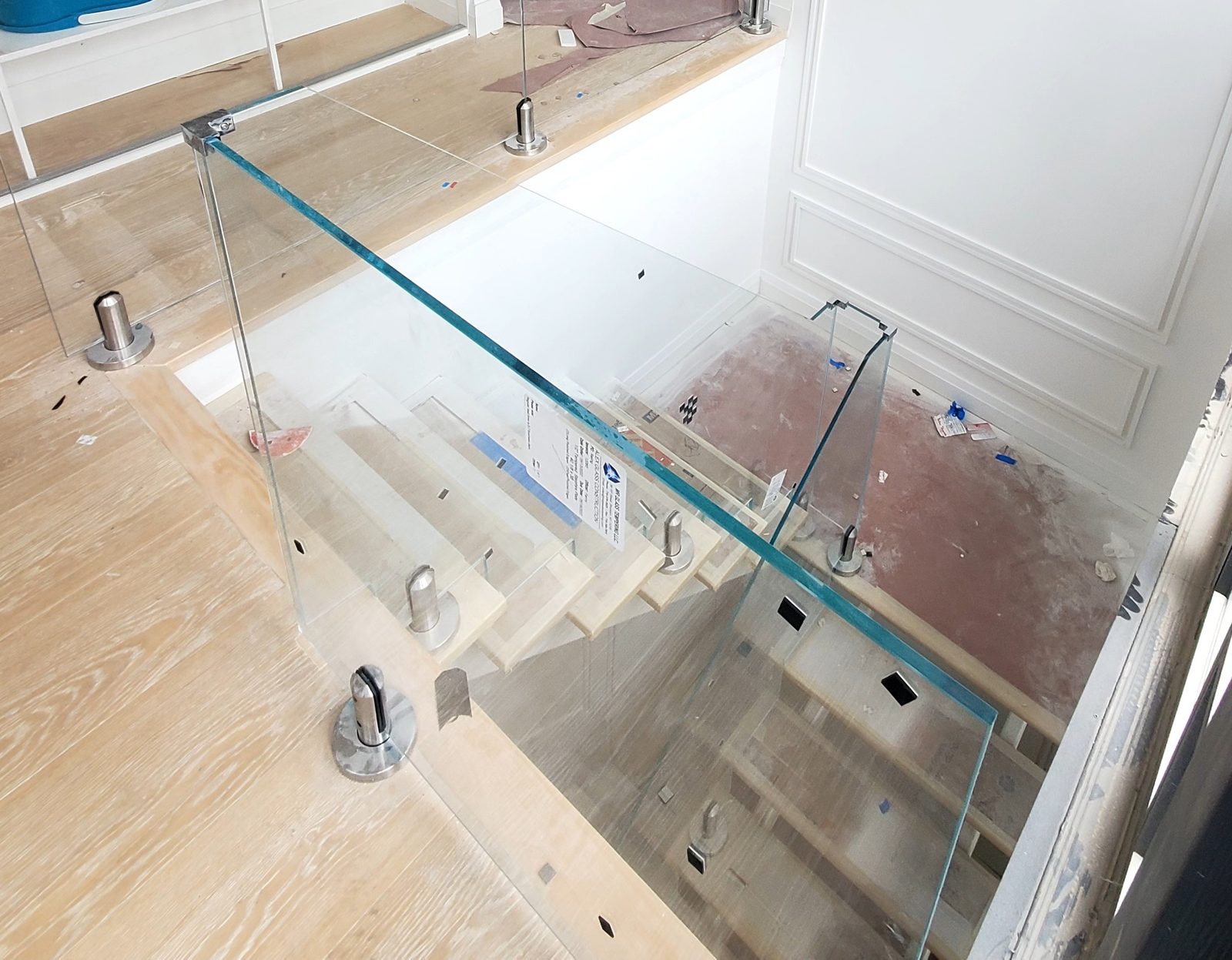 Glass railing at the upper stair landing of the 300 East 90th Street penthouse, with stainless steel spigots and a corner clamp joining two panels