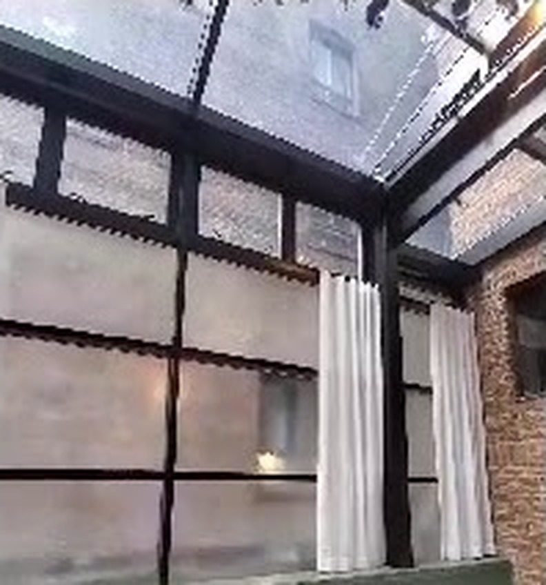 Interior of the sunroom at the Civilian Hotel showing the glazed wall, glass roof and exposed brick