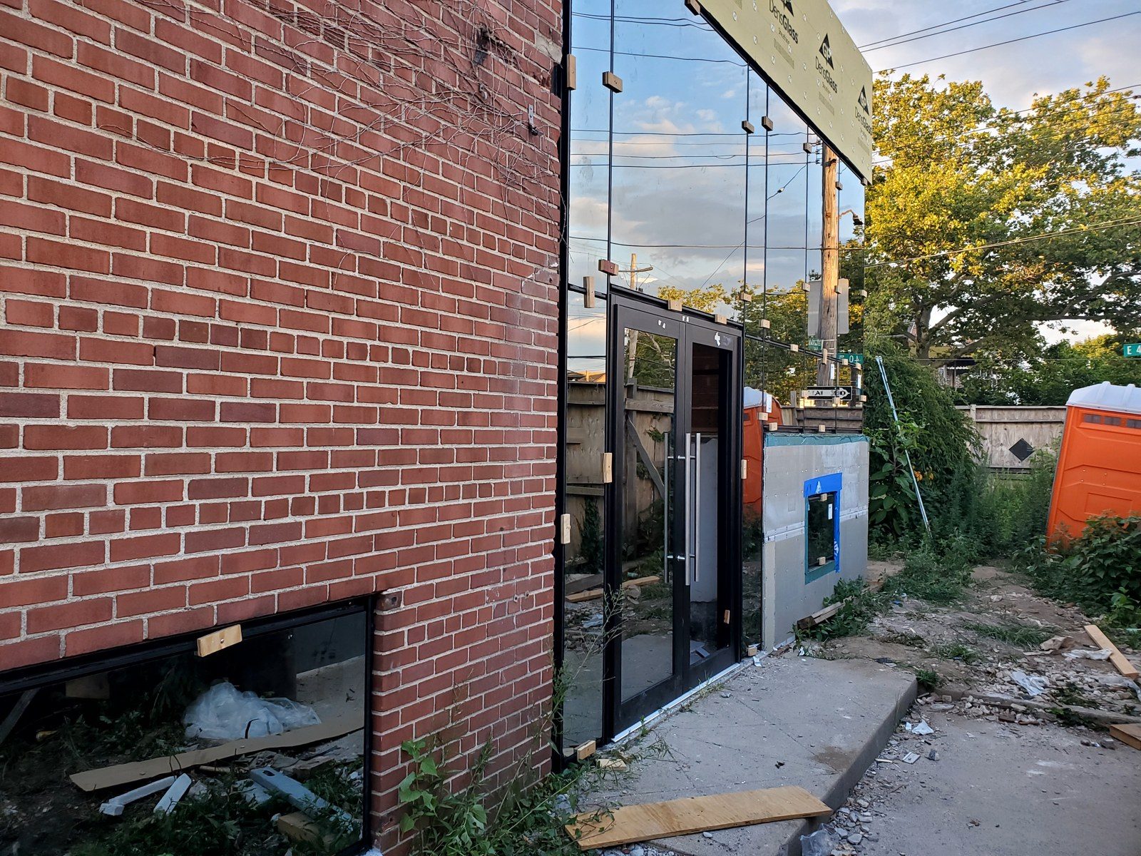 Entrance doors and curtain wall glass installed in the brick shell of 3915 Flatlands Avenue, Brooklyn, during construction