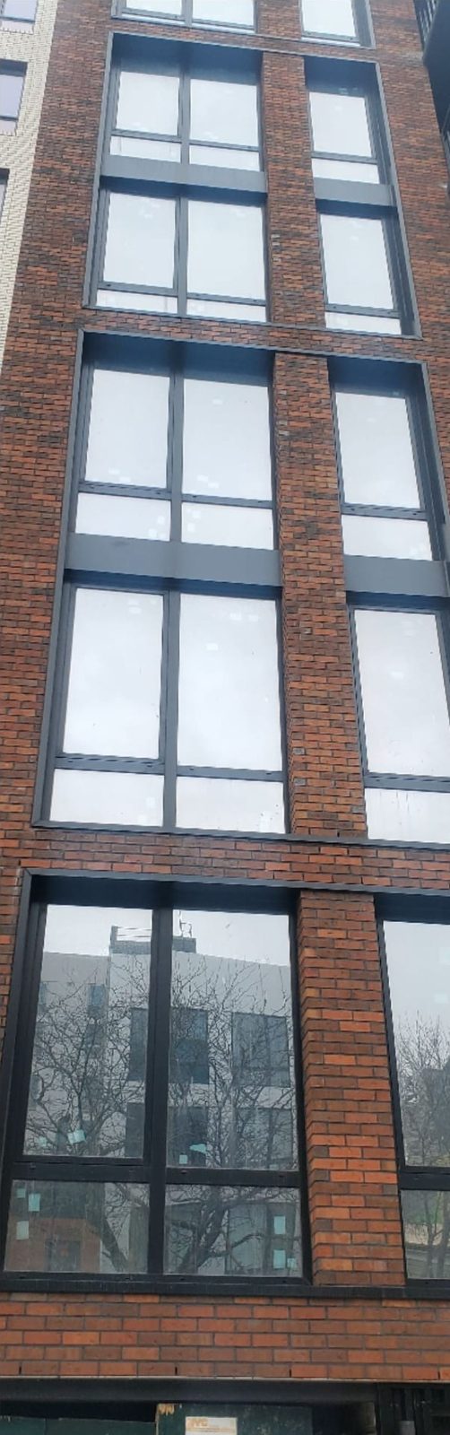 Black metal panels and sheet metal surrounds around the windows in the brick facade at 514 Herkimer Street, Brooklyn
