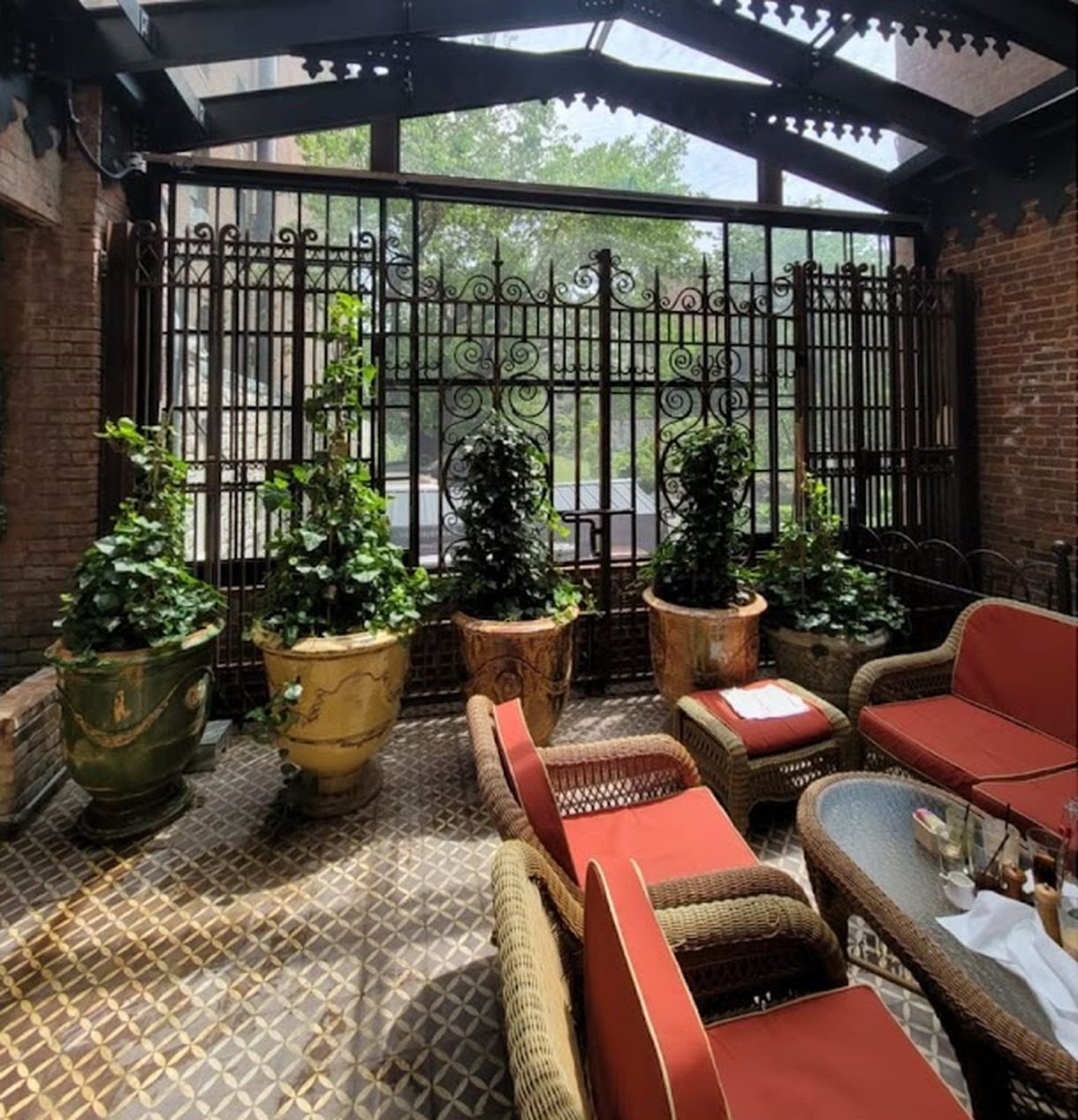 The Bowery Sunroom at 60 Herbert Avenue, Closter, NJ: glass walls behind ornate ironwork, a pitched glass roof and a patterned tile floor