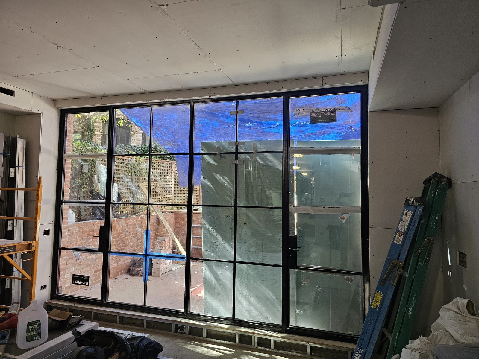 Tall black SIMPAS aluminum in-swing door with divided lites opening onto a terrace, seen from inside on East 71st Street