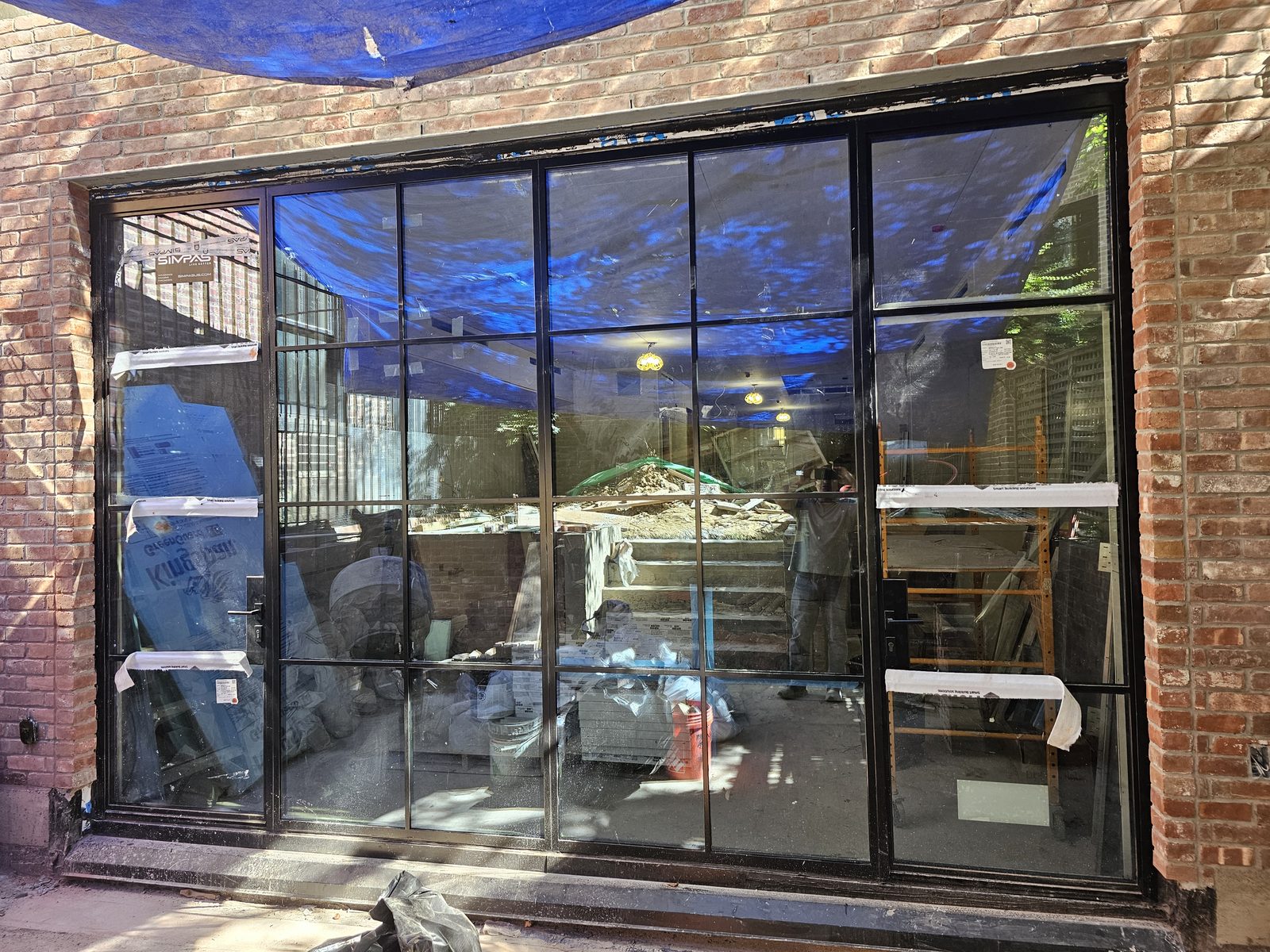 Exterior view from the terrace of a black divided-lite SIMPAS in-swing door set in brick on East 71st Street