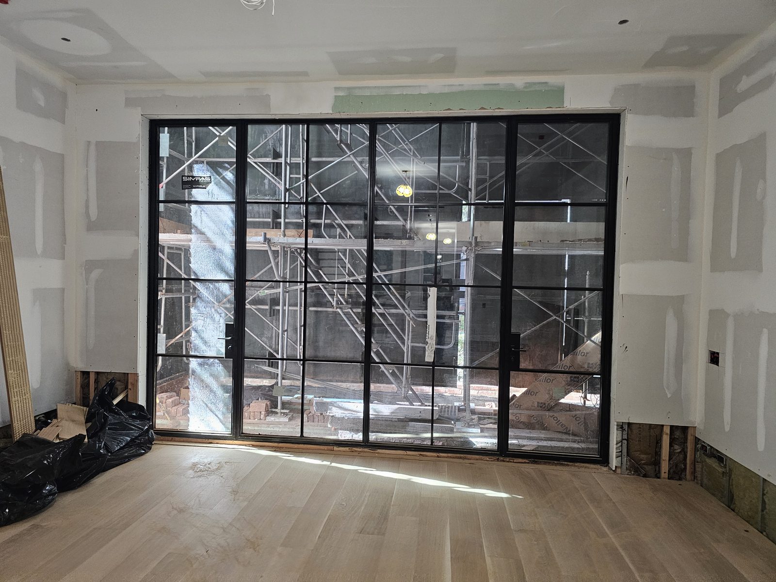 Black SIMPAS divided-lite in-swing door in a room with the oak floor laid, East 71st Street Manhattan