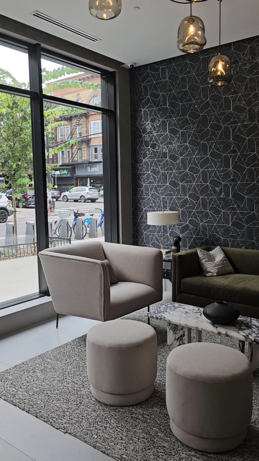 Lobby lounge at 711 Franklin Avenue, Crown Heights, Brooklyn, with floor-to-ceiling glass in black aluminum storefront frames facing the street