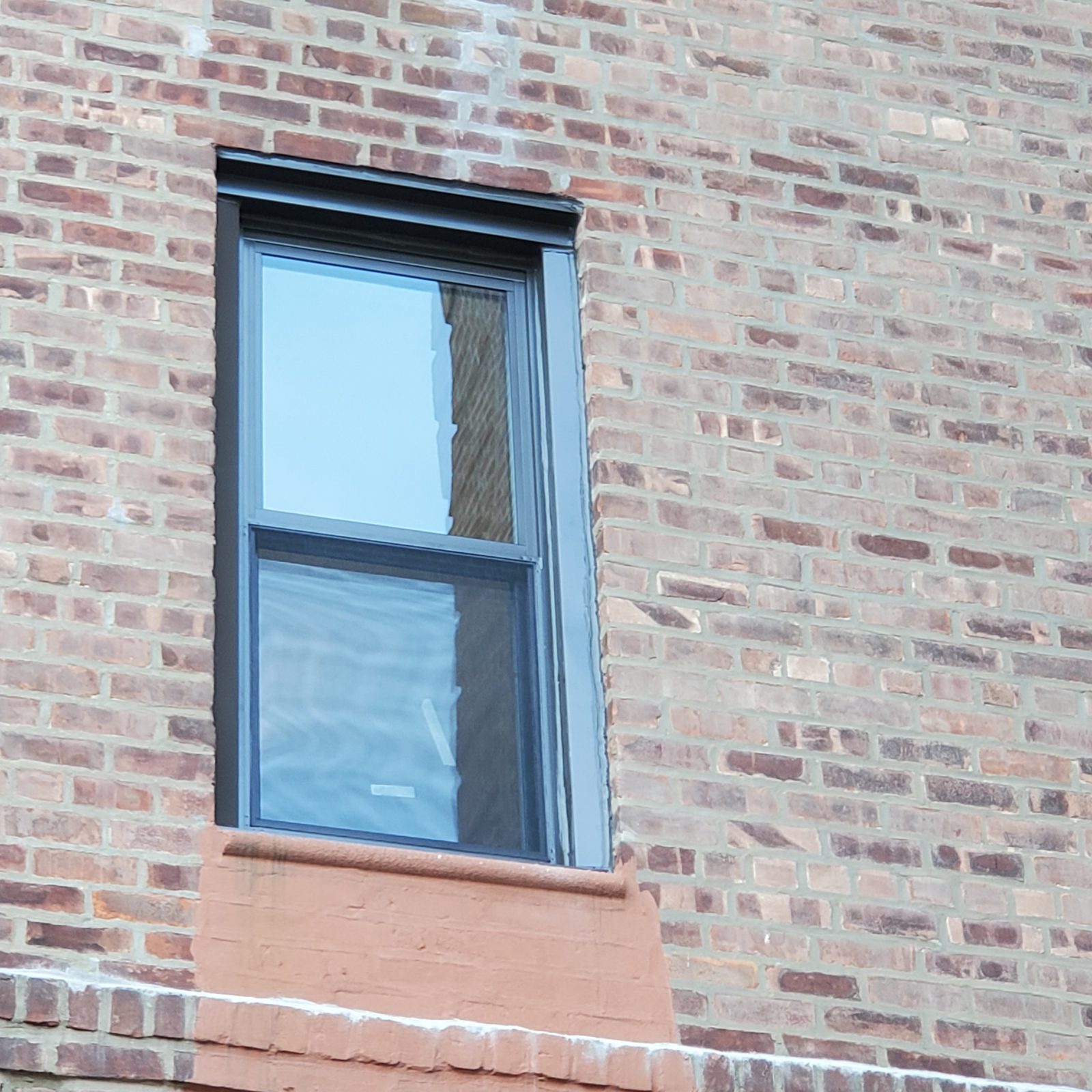 Dark-framed double-hung replacement window with exterior trim at head and jambs, Brighton Beach, Brooklyn