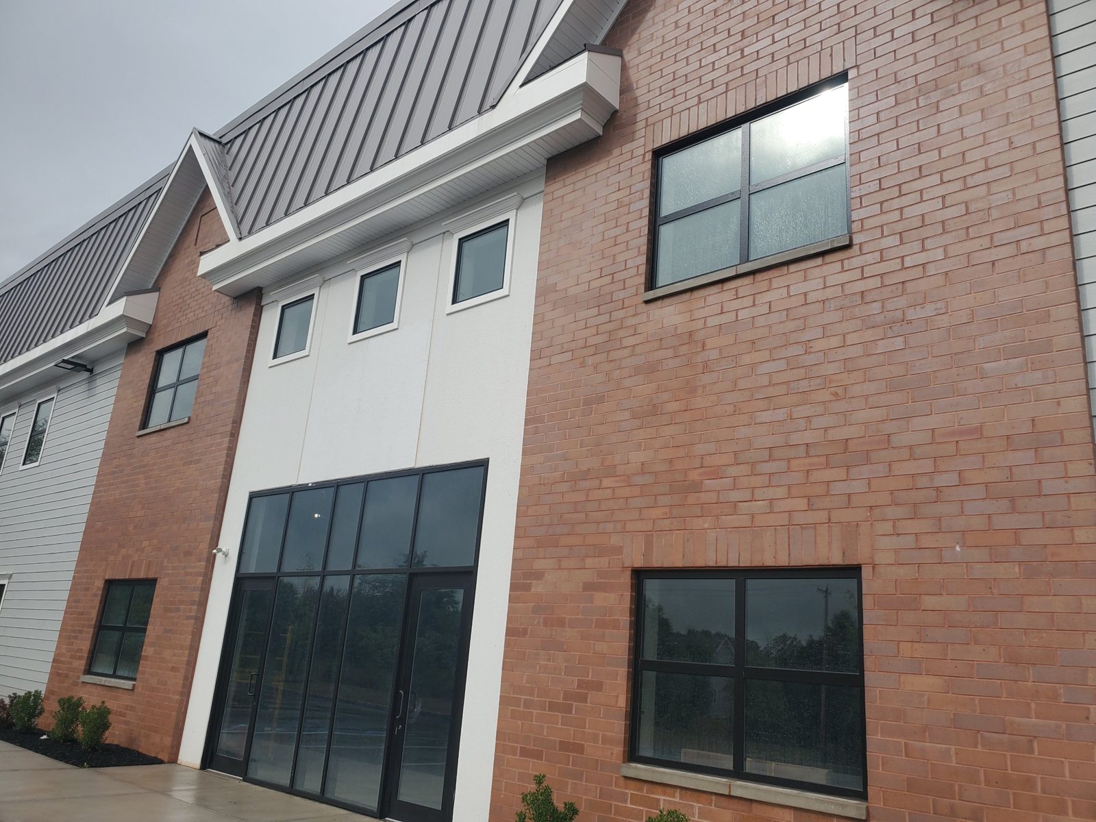 Entrance bay of the Central New Jersey warehouse with YKK storefront, square windows above and four-light Alutech windows in the brick