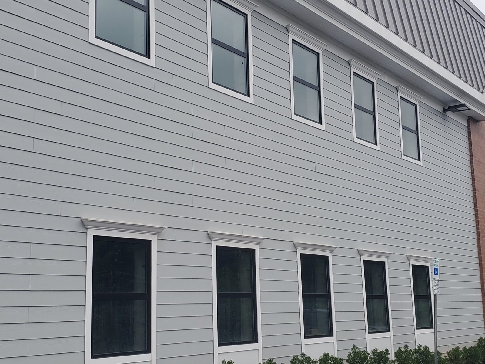 Dark Alutech aluminum windows in white trim with molded heads on gray siding at a warehouse in Central New Jersey