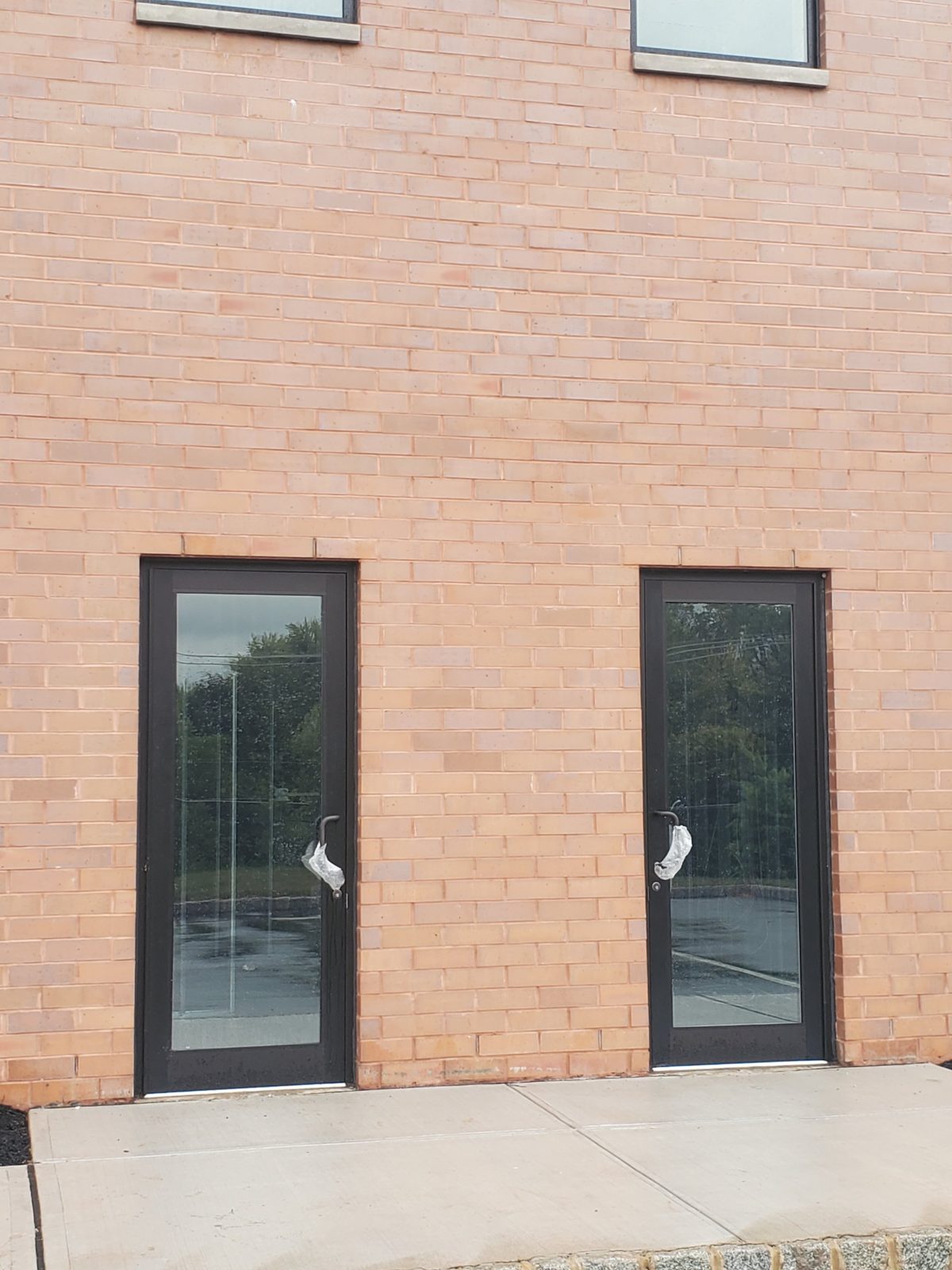 Two dark aluminum and glass doors set in a brick wall at a warehouse in Central New Jersey