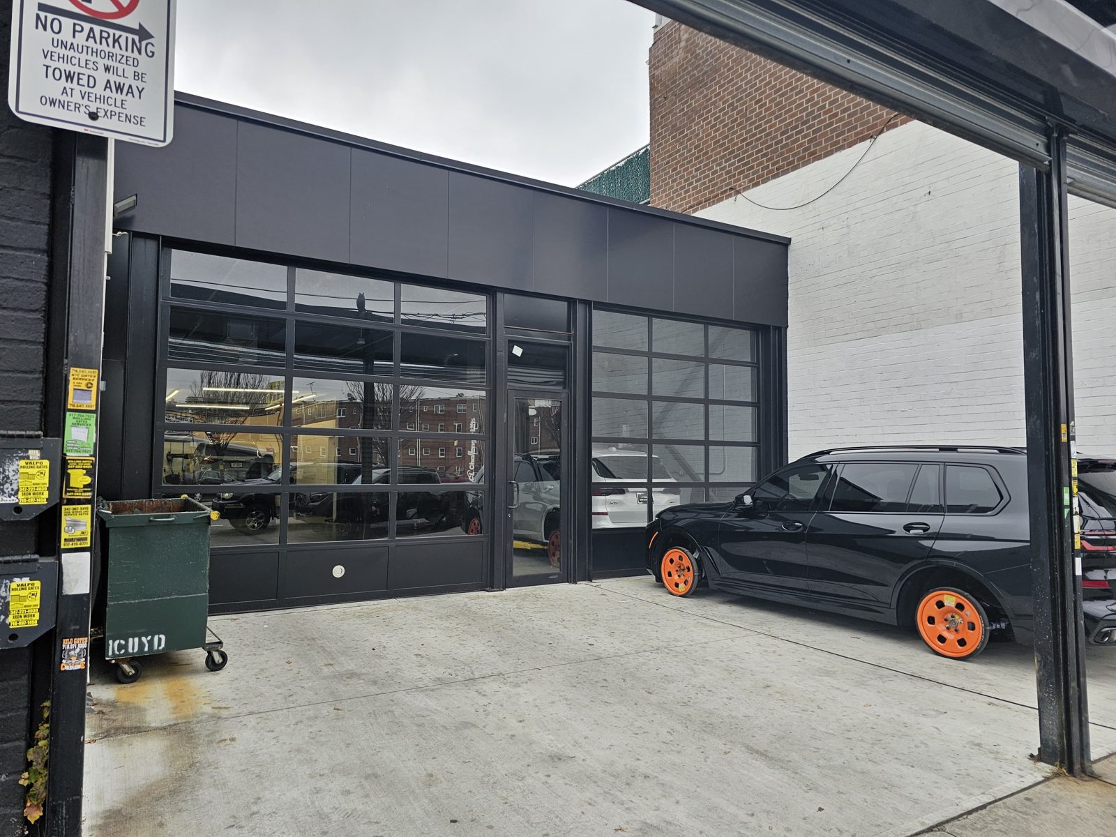 New black storefront and aluminum composite panel facade with a commercial glass door and transom at the Grand Prix Custom auto business on Flatbush Avenue, Brooklyn
