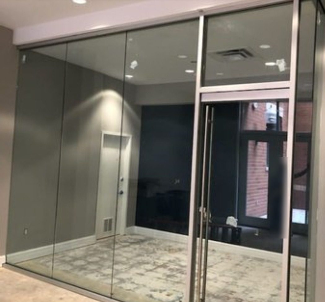 Floor-to-ceiling glass office partition with butt-jointed panels and a framed glass door with transom in a Manhattan office