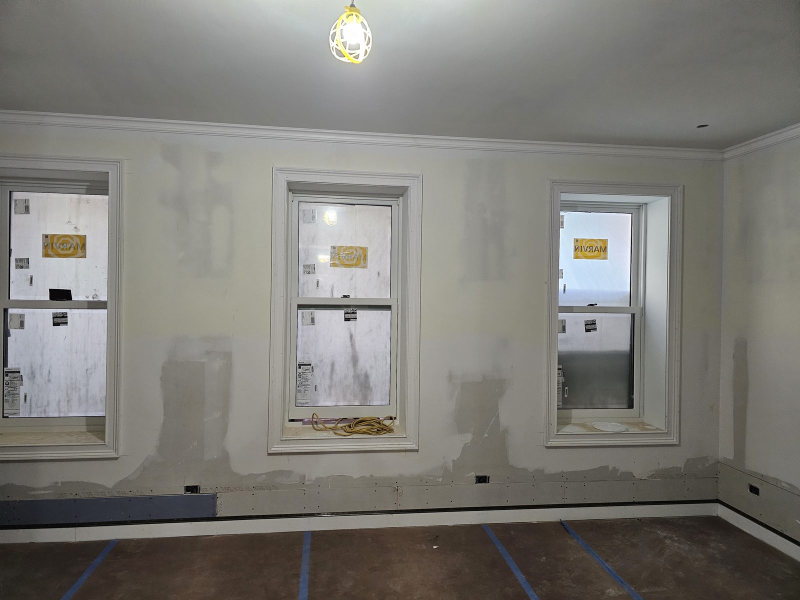 Three Marvin Ultimate wood double-hung windows with white casings in a room under construction on East 71st Street