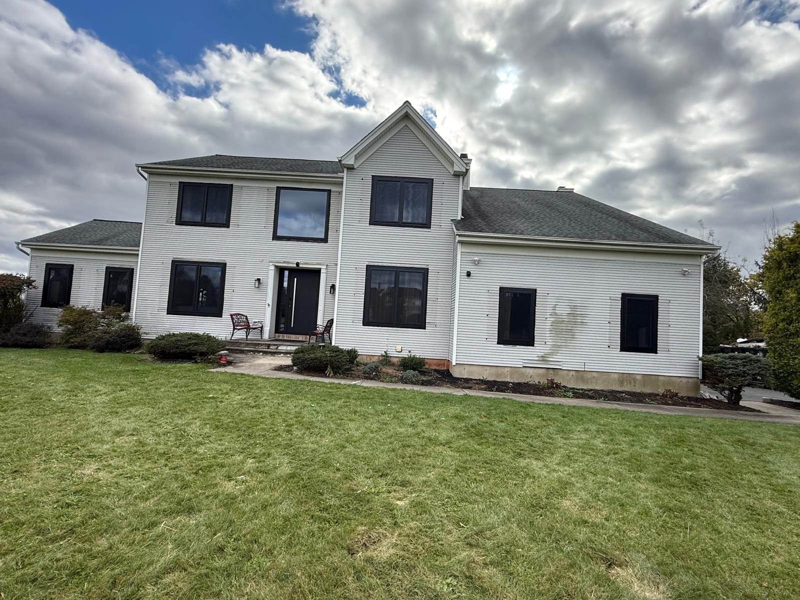 Front of the colonial house in Somerset, NJ with black aluminum windows installed on both floors and the new black entry door