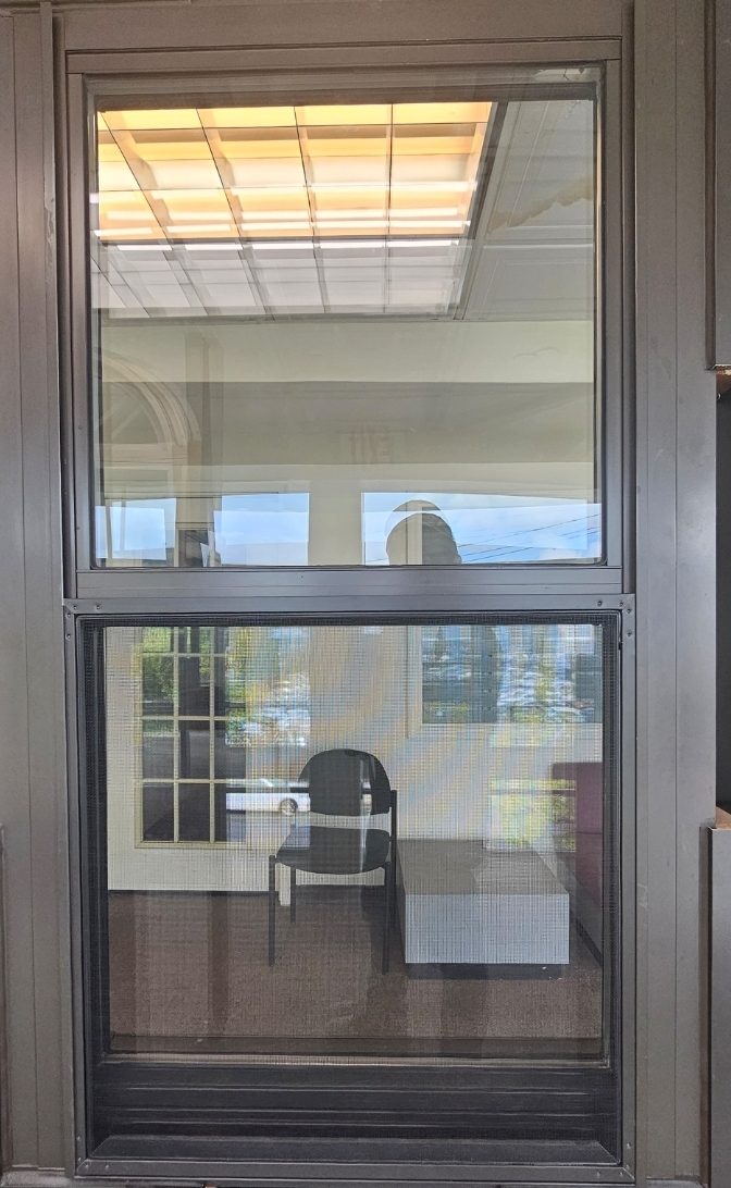 Crystal Series 5500 double-hung tilt window sample in a dark bronze aluminium frame with both sashes and the insect screen in place