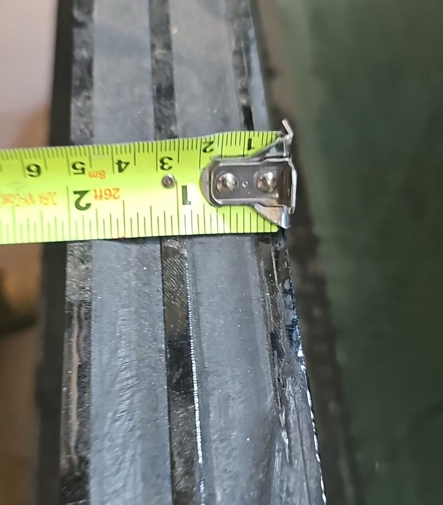 Edge of a triple-glazed insulating glass unit sample with a tape measure across it, showing three lites of glass and two spacers